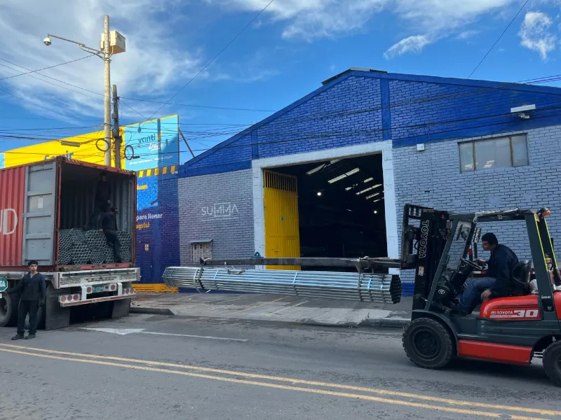 Montacargas descargando un contenedor frente a una bodega